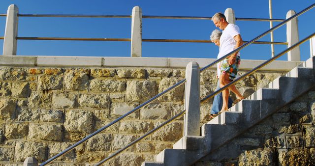 Senior caucasian couple holding hands and walking down the stairs by sea - Download Free Stock Photos Pikwizard.com