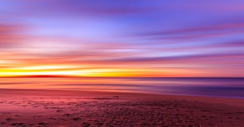Sunset Painting Over Beach Shoreline with Vibrant Long-Exposure Color Streaks