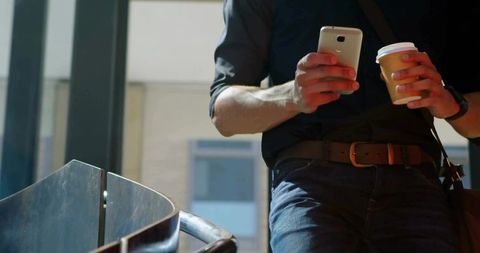 Modern Professional with Busy Lifestyle Holding Smartphone and Coffee