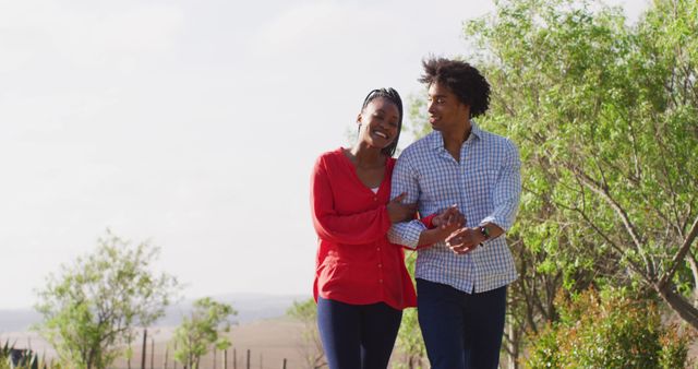 Happy african american couple walking together and holding hands on sunny day, slow motion. Outdoor lifestyle, countryside and nature concept.