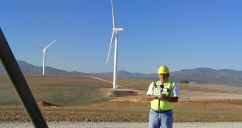 Engineer Operating Drone near Wind Turbines in Countryside