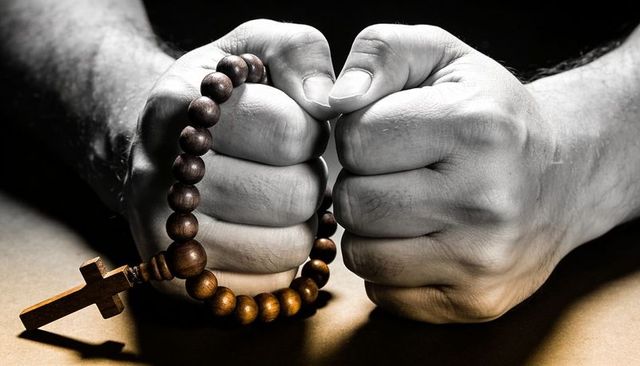 Clenching hands holding wooden rosary beads, cross casting shadow, dramatic chiaroscuro