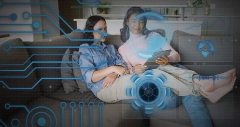 Two women exploring augmented reality on tablet with holographic HUD and cozy living room