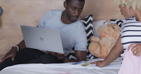 Couple discussing baby clothes while shopping online in bedroom