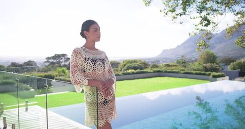 African american woman relaxing on luxury villa terrace by infinity pool with mountain view