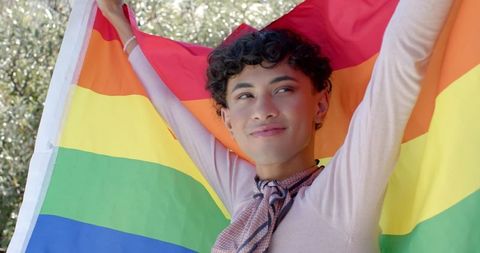 Person Holding Rainbow Flag in Outdoor Celebration of Diversity