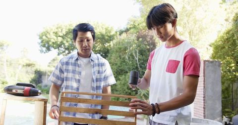 Father and teenage son crafting outdoor diy furniture