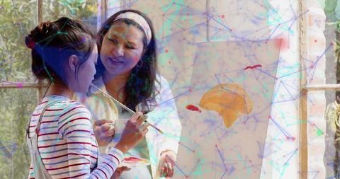 Mentor guiding young artist during sunlit studio painting lesson with canvas and easel