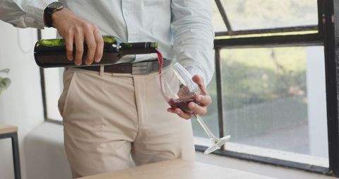 Elegantly Pouring Red Wine in Sunlit Modern Office Setting - Download Free Stock Images Pikwizard.com