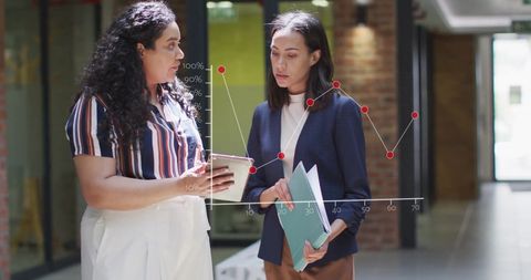 Diverse Female Professionals Analyzing Financial Data in Office Hallway