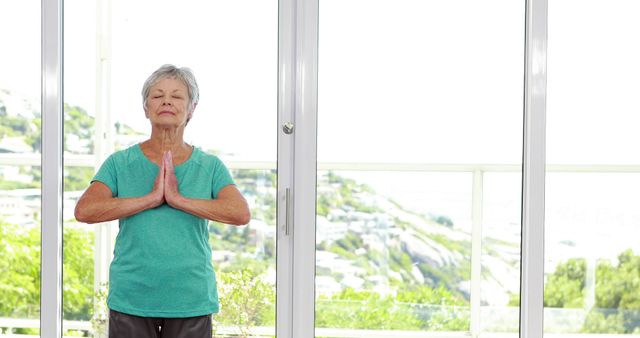 Senior Woman Meditating in Bright Room with Glass Wall - Download Free Stock Images Pikwizard.com