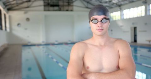Male swimmer in swim cap at indoor pool shows confidence