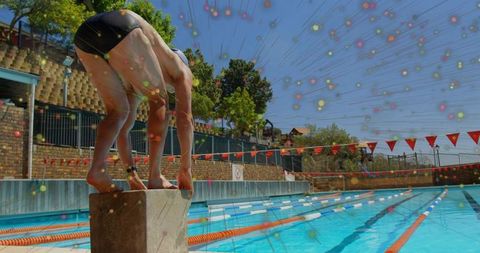 Athlete crouching on starting block at outdoor lap pool