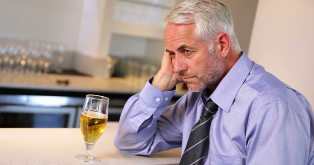 Middle-aged man in business suit sitting at bar counter, drinking beer, looking stressed and deep in thought. Perfect for illustrating themes of work stress, loneliness, alcohol consumption, mid-life crisis, or mental health awareness. Suitable for use in articles, blogs, advertisements, and education materials about stress management, mental health, and social issues.