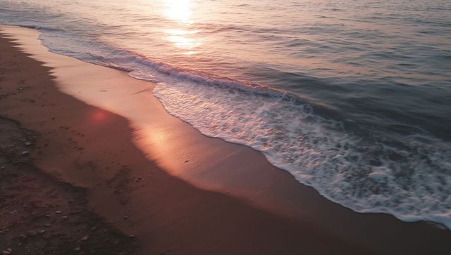 Golden hour waves lapping sandy shoreline with sun reflection and foamy tide, serene coast