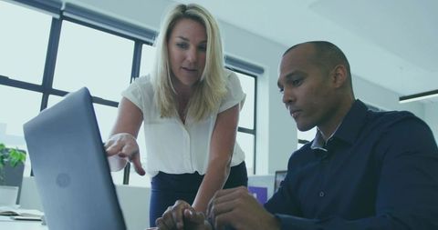 Coworkers Collaborating over Laptop in Bright Office Environment