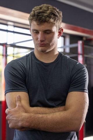 Young boxer standing cross-armed in ring looking contemplative