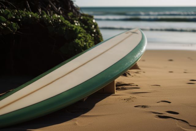 Surfboard resting on sandy beach with ocean waves in background, ideal for travel and adventure promotions, surf-related blogs, summer vacation brochures.