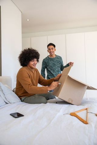 Diverse Friends Organizing in Minimalist Bedroom with Moving Box