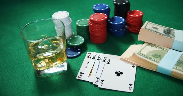 Playing cards, casino chips, bundle of us dollar and glass of beer on poker table in casino 