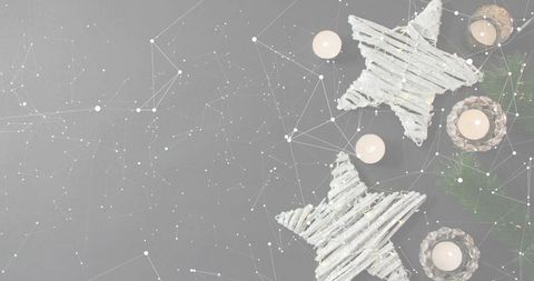 Cozy festive flatlay featuring twig star ornaments and glowing tea lights on gray tabletop