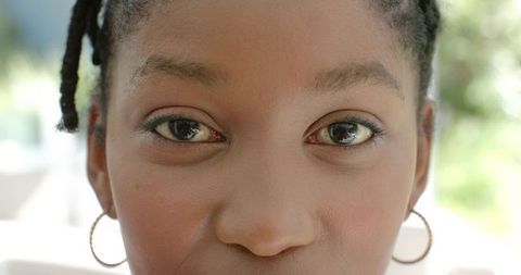 Closeup african american woman gazing with braided hair and gold hoop earrings, makeup