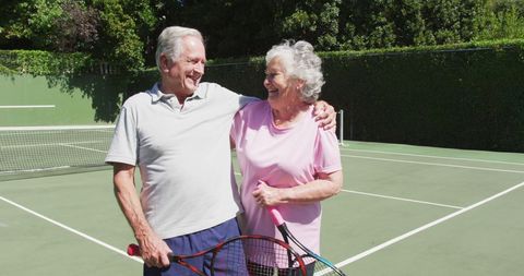 Happy Senior Couple Embraces on Tennis Court