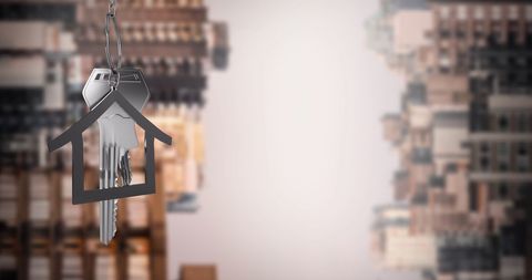 Silver house key hanging against modern cityscape background