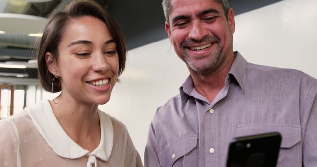 Colleagues Smiling and Looking at Smartphone in Office - Download Free Stock Images Pikwizard.com