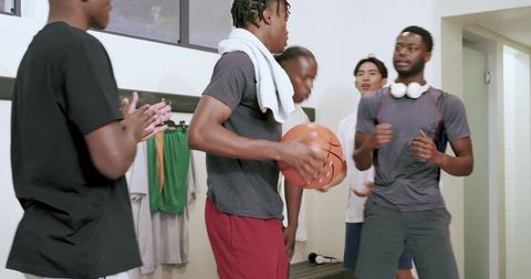 Basketball teammates bonding in locker room holding basketball, gearing up for game