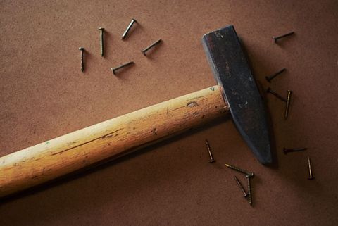 Vintage hammer with loose nails on brown surface