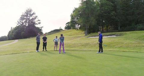 Family Observing Golfer on Putting Green