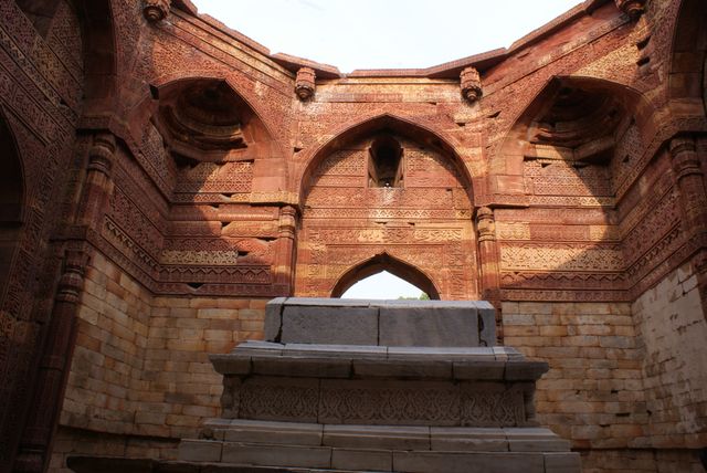 This image captures an impressive historical stone tomb featuring detailed archways and red sandstone architecture. It showcases the intricate design and cultural heritage of an ancient site, making it suitable for use in articles and websites related to history, architecture, archaeology, heritage tourism, and cultural studies.