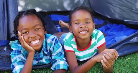 Happy Children Lounging Outdoors in Front of Tent