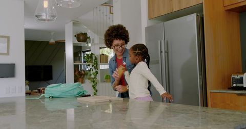 Mother and Daughter Packing Lunch in Contemporary Kitchen