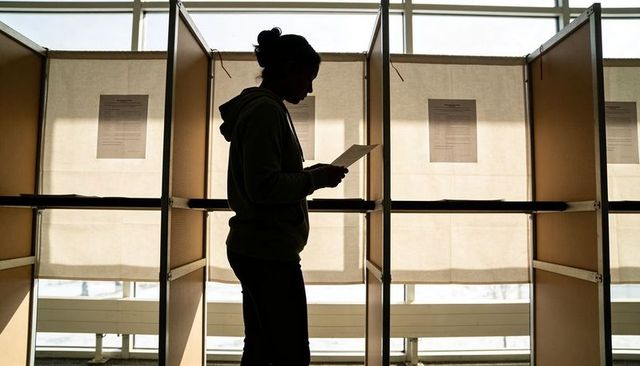 Silhouette voter reading ballot at polling booths backlit privacy civic participation focus