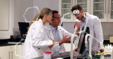 Medical Researchers Collaborating Over Blood Sample While Reviewing Digital Data On Monitor