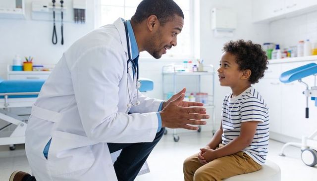 Pediatrician kneeling and talking with smiling child in bright clinic exam room
