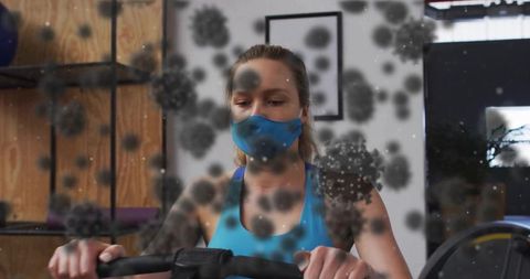 Focused Woman Cycling with Mask and Airborne Particles in Gym
