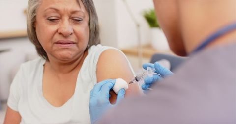 Healthcare worker administering vaccine to senior woman in clinic