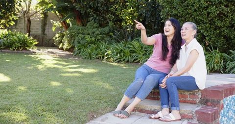Asian mother and daughter bonding outdoors near pool