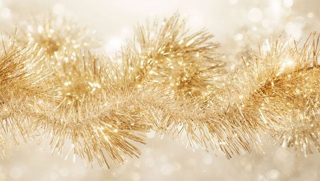 Shimmering gold tinsel garland catching warm light with glittering bokeh metallic sparkle