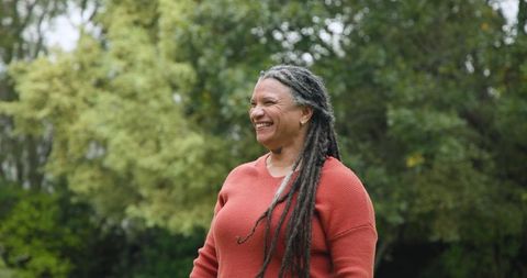 Smiling Senior Woman with Long Braids Enjoying Nature in Autumn Ensemble