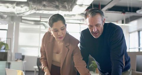 Professionals collaborating and reviewing strategy at laptop in modern open-plan office
