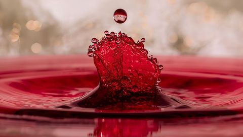 Rising crimson crown splash with suspended droplet, glossy ripples and macro detail