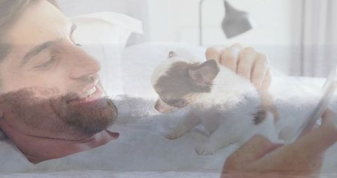 Man relaxing with puppy and smartphone in cozy bedroom