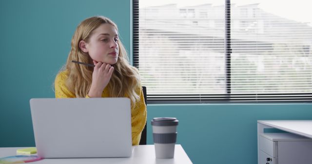 Woman in Bright Office Contemplating While Holding Pencil Near Laptop - Download Free Stock Images Pikwizard.com