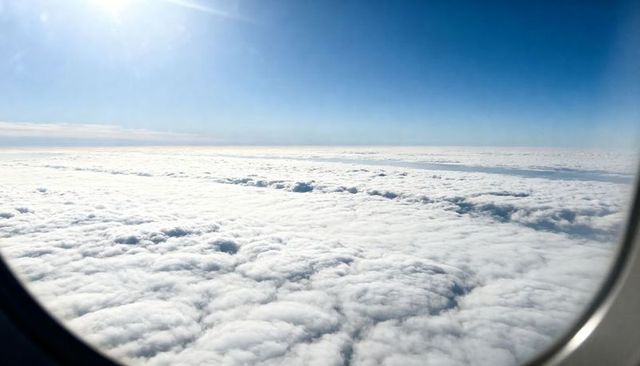 Sunlit Above-Cloud Panorama Through Airplane Window Showing Stratocumulus Cloud Deck