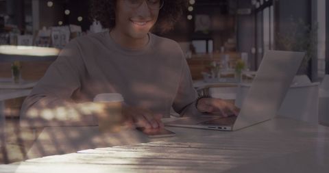 Smiling Woman Using Laptop in Busy Cafe Setting