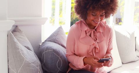 Smiling Woman Texting on Smartphone Inside Cafe